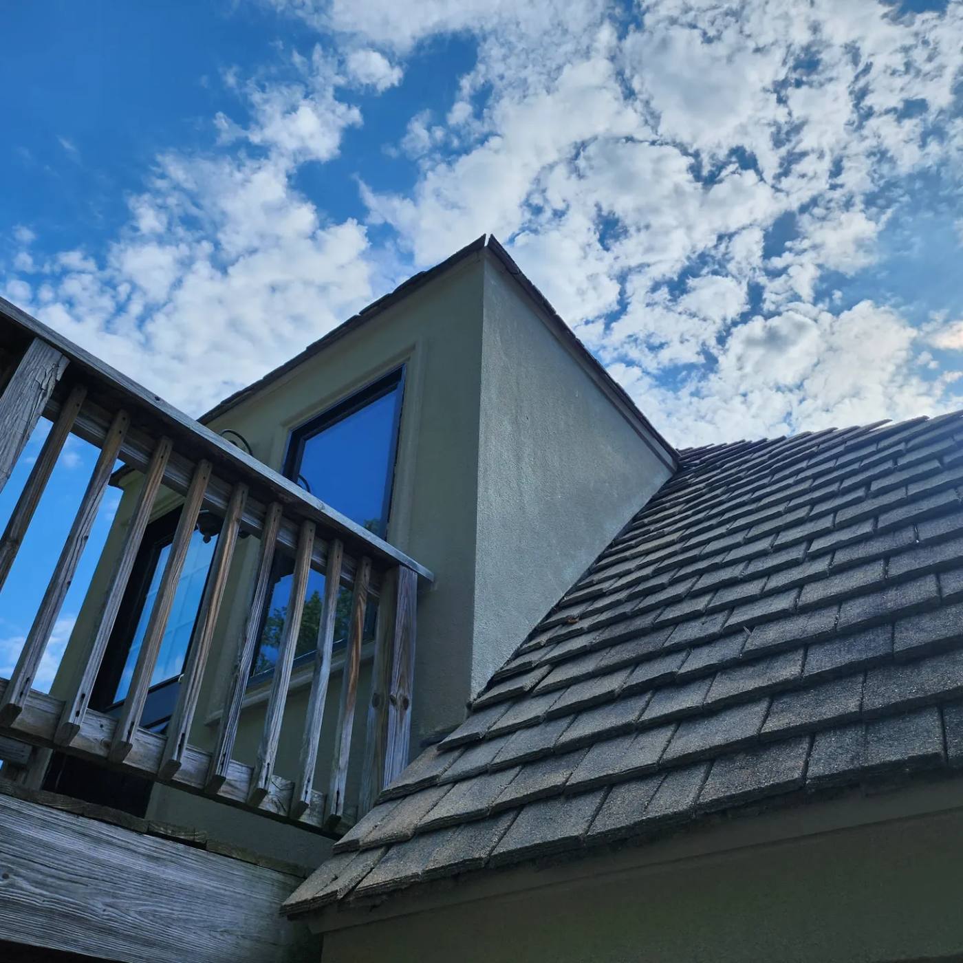 A residential roof and second-storey balcony, photographed from below.